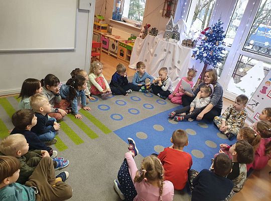 Mama Nadii czyta dzieciom, które siedzą na dywanie