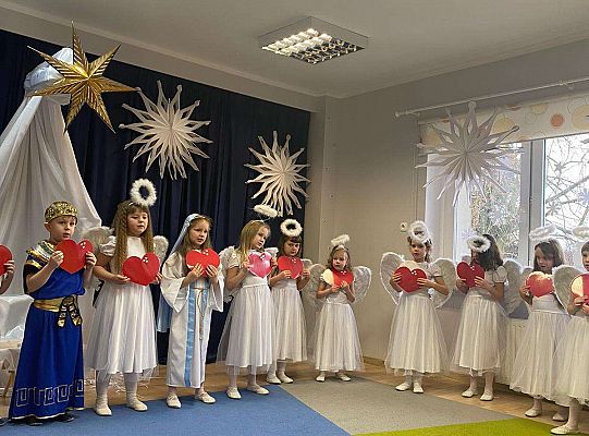 Dziewczynki przebrane za aniołków śpiewają piosenkę a przed sobą trzymają serduszka