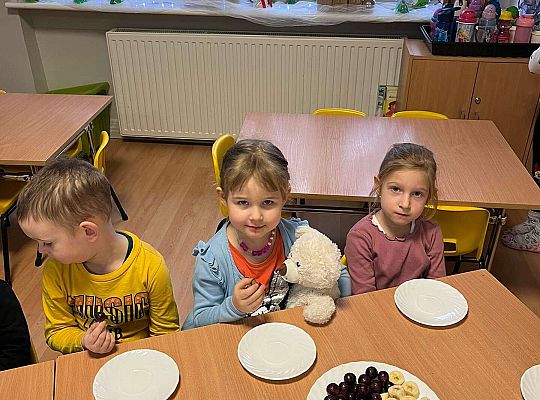 Dzieci przy wspólnym stole jedzą urodzinowe owoce