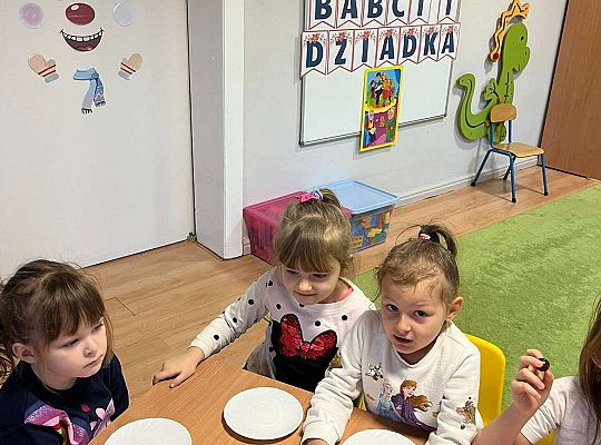 Dzieci przy wspólnym stole jedzą urodzinowe owoce