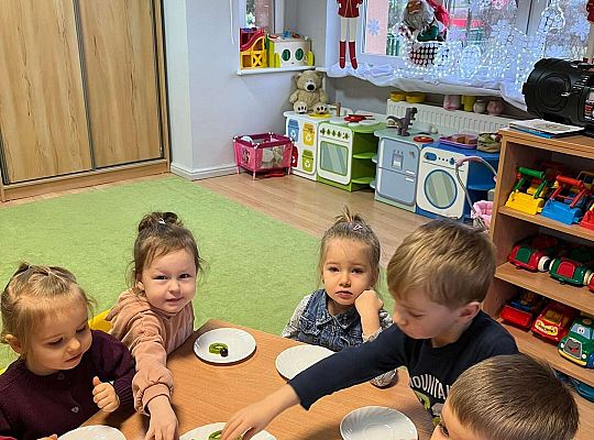 Dzieci przy wspólnym stole jedzą urodzinowe owoce