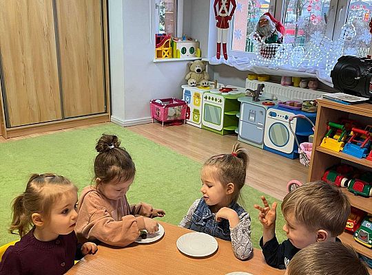 Dzieci przy wspólnym stole jedzą urodzinowe owoce