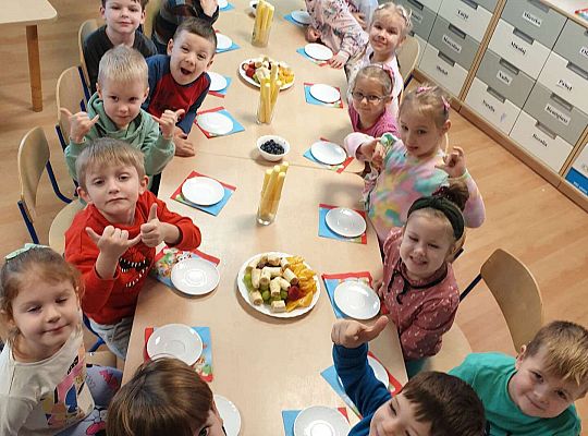 Wspólne biesiadowanie grupy przy stole z owocami