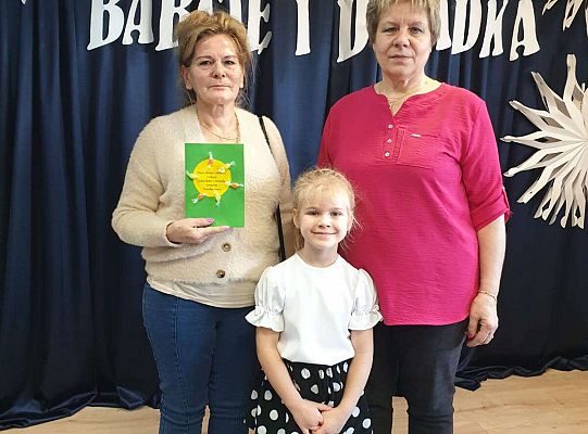 Dwie babcie stoją z wnuczka na tle dekoracji