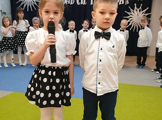 Dziewczynka mówi wiersz przez mikrofon a chłopiec stoi obok