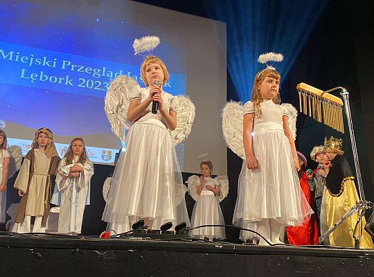 Dwie dziewczynki przebrane za aniołki na scenie w otoczeniu innych dzieci