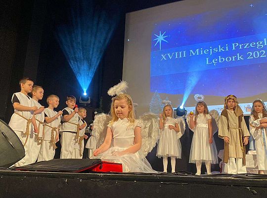 Dziewczynka przebrana za aniołka gra na cymbałkach