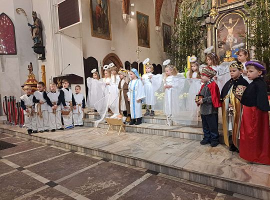 Dzieci w jasełkowych strojach stoją przed ołtarzem w kościele