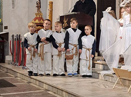 Ksiądz zaprasza na "Jasełka" a dzieci stoją obok