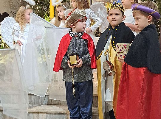 Trzej Królowie stoją przed ołtarzem w kościele a obok aniołki