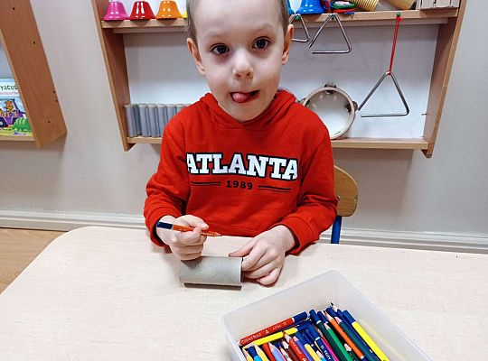 Chłopiec wykonuje instrument muzyczny z rolki po papierze toaletowym