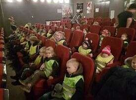 Dzieci siedzą w fotelach i oglądają przedstawienie