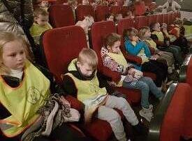 Dzieci siedzą w fotelach i oglądają przedstawienie
