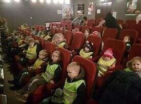 Dzieci siedzą w fotelach i oglądają przedstawienie