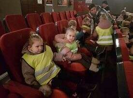 Dzieci siedzą w fotelach i oglądają przedstawienie