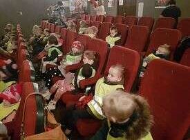 Dzieci siedzą w fotelach i oglądają przedstawienie
