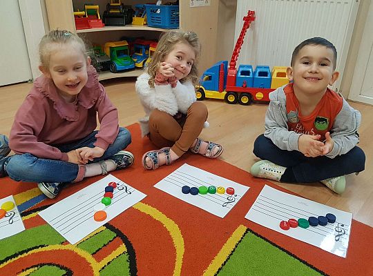 Dzieci układają zakrętki na pięciolinii