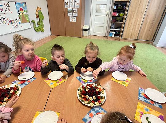 Dzieci jedzą urodzinowe owoce