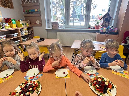 Dzieci jedzą urodzinowe owoce