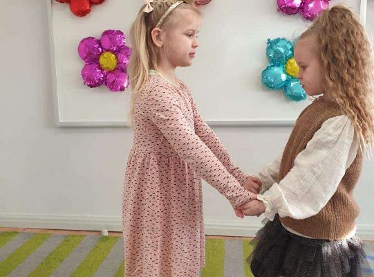 Dziewczynka trzyma za ręce solenizantkę