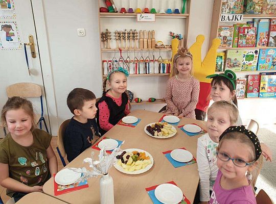 Grupa dzieci siedzi przy urodzinowym stole
