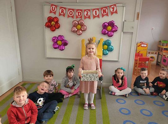 Natalka stoi pośród dzieci z pudełkiem z łakociami