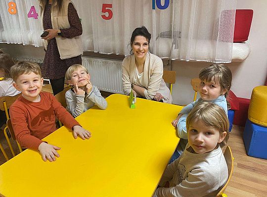 Czwórka dzieci wraz z wychowawczynią siedzi przy stole
