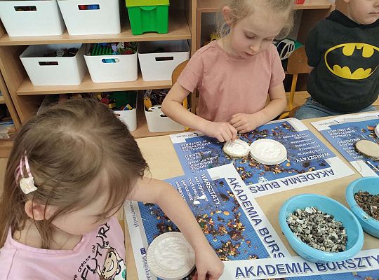 Dzieci układają bursztyn i muszelki