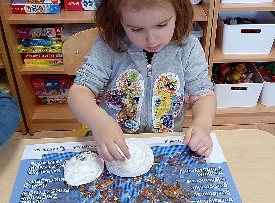 Dzieci układają bursztyn i muszelki