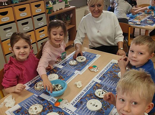 Dzieci wykonują prace z bursztynem pod kierunkiem nauczycielki