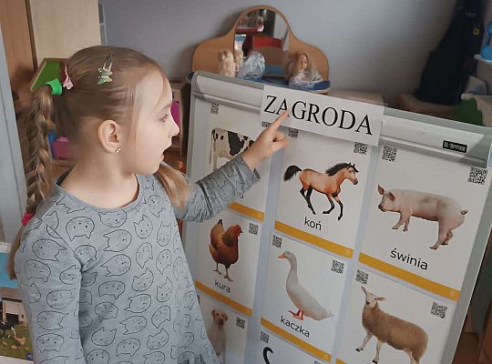 Dziewczynka czyta napis zagroda