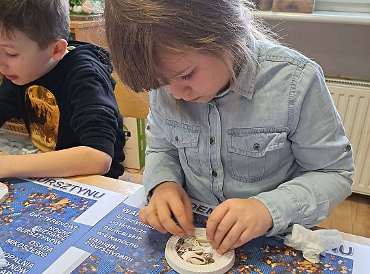 Dziewczynka wykonuje prace z bursztynem