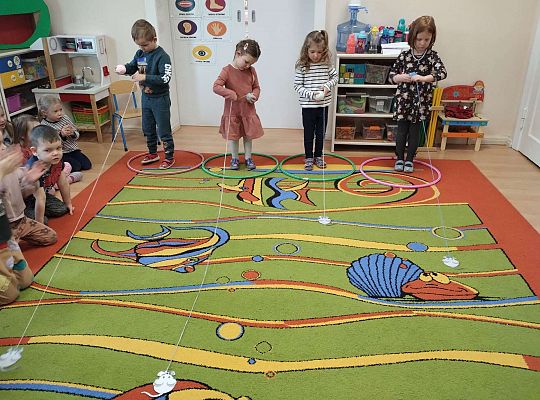 Dzieci zwijają kłębek wełny z myszką na końcu