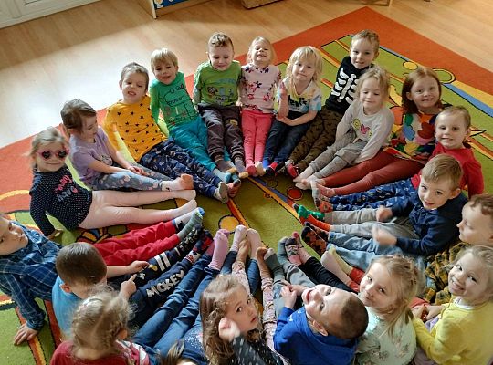 Dzieci siedzą na podłodze pokazując kolorowe skarpetki