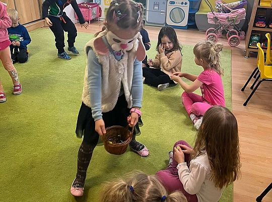 Dziewczynka częstuje dzieci czekoladowymi jajkami