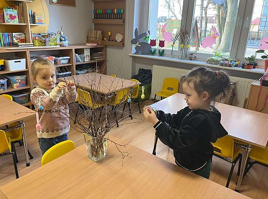 Dzieci wieszają jajeczka na gałązkach