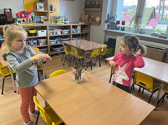 Dzieci wieszają jajeczka na gałązkach