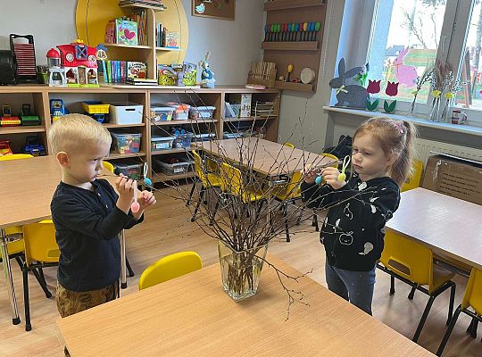 Dzieci wieszają jajeczka na gałązkach