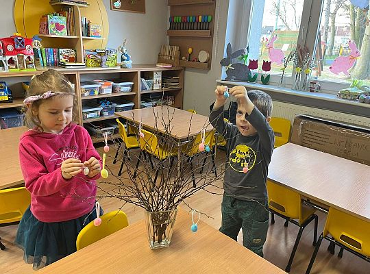 Dzieci wieszają jajeczka na gałązkach