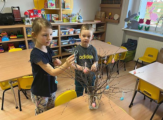 Dzieci wieszają jajeczka na gałązkach