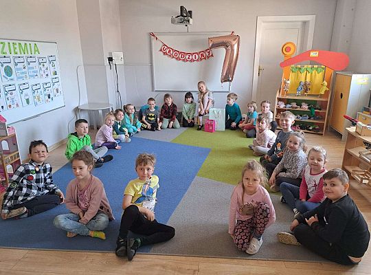 Grupa dzieci siedzi wokoło solenizantki