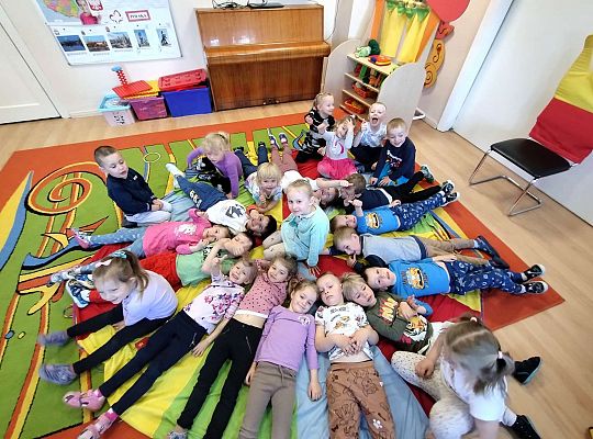 Dzieci leżą na podłodze wkoło jubilatki