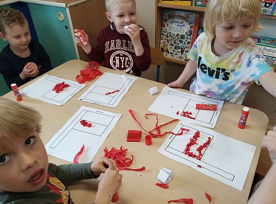 Dzieci wyklejają flagę kulkami z bibuły