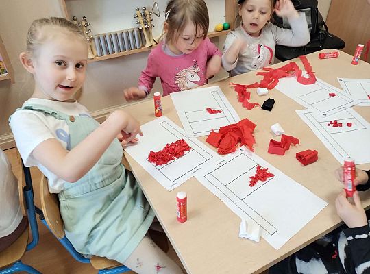 Dzieci wyklejają flagę kulkami z bibuły