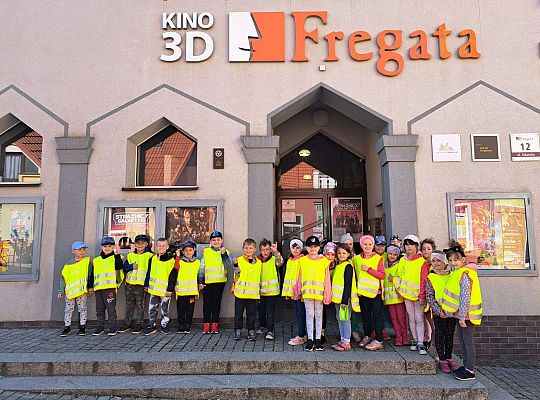 Dzieci stoją ustawione przed kinem