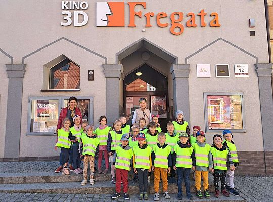 Dzieci stoją ustawione przed kinem