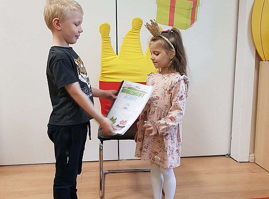 Chłopiec wręcza jubilatce album urodzinowy