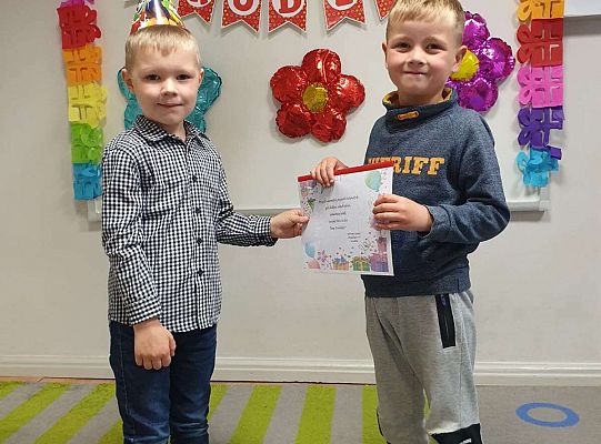 Chłopiec wręcza album solenizantowi