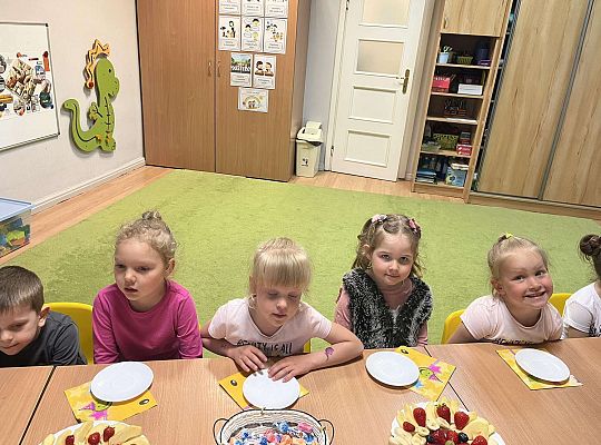 Dzieci siedzą przy urodzinowym stole