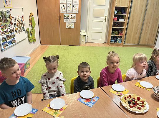 Dzieci siedzą przy urodzinowym stole